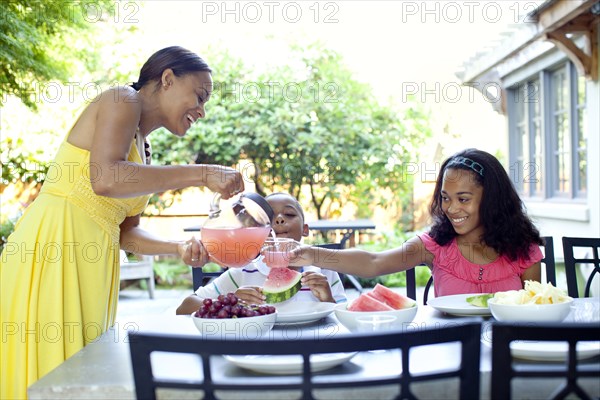 African American woman serving juice to daughter