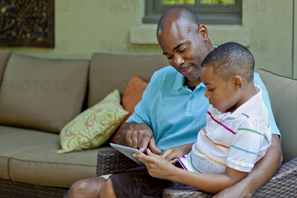 African American father and son using digital tablet
