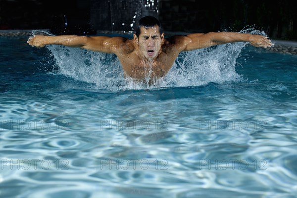 Pacific Islander man swimming in swimming pool