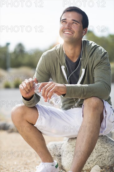 Mixed race man drinking water after exercise