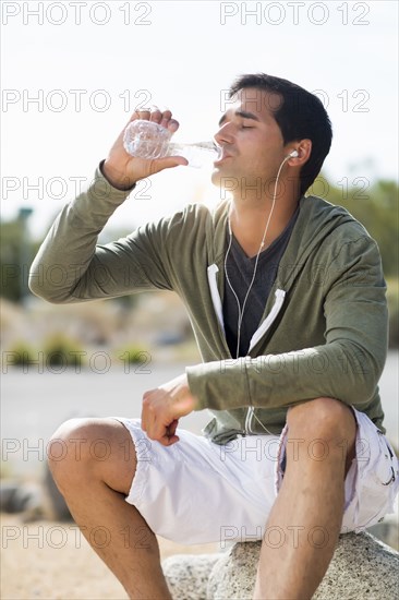 Mixed race man drinking water after exercise