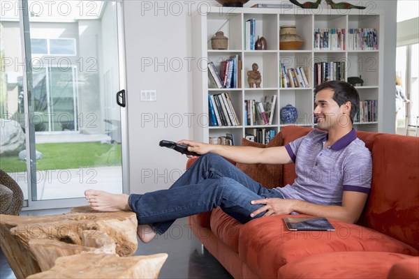 Mixed race man sitting on sofa watching television