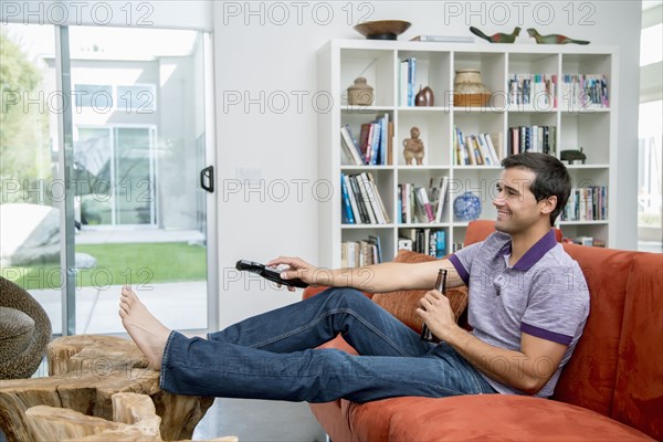 Mixed race man sitting on sofa watching television