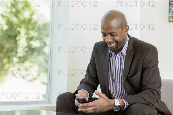 Black businessman text messaging on cell phone