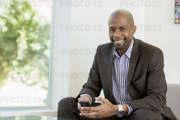 Black businessman text messaging on cell phone