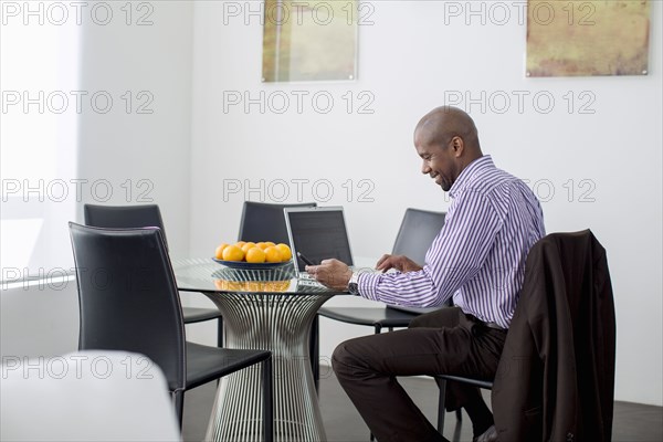 Black businessman using laptop and cell phone