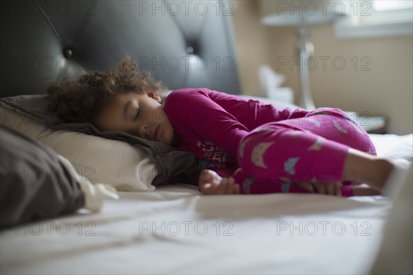 Mixed race girl sleeping in bed