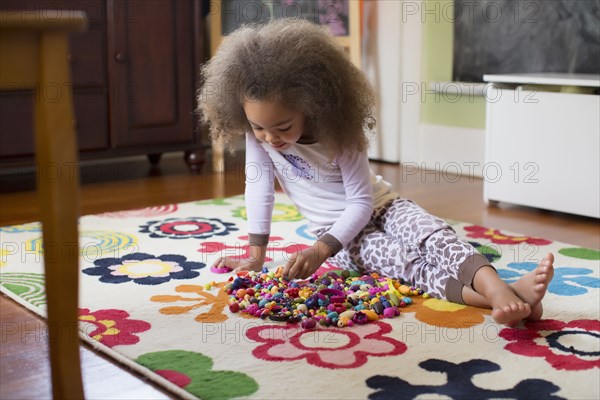 Mixed race girl playing with toys on floor