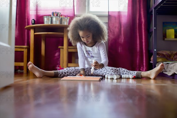 Mixed race girl sitting on floor drawing