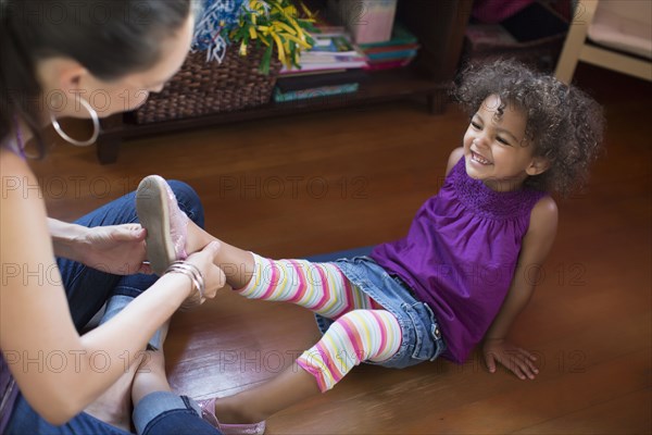 Mother putting shoes on daughter
