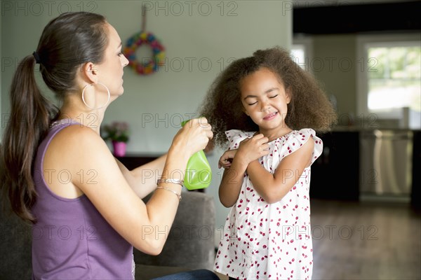 Mother spraying daughter's hair