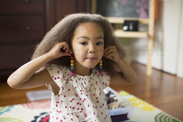 Mixed race girl trying on earrings