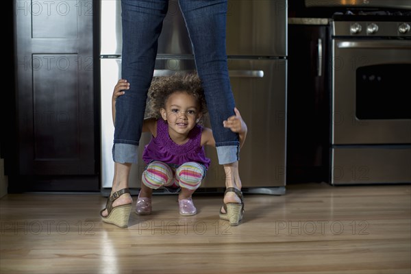 Mixed race girl playing underneath mother's legs