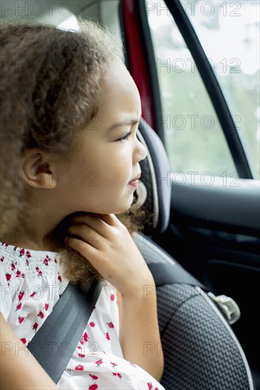 Mixed race girl sitting in car seat