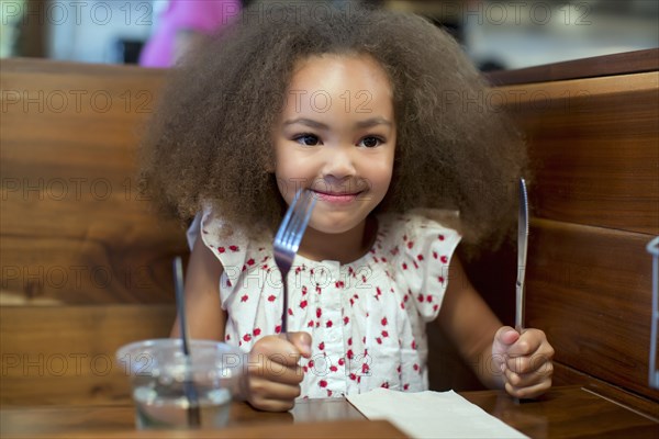 Mixed race girl waiting for food in restaurant