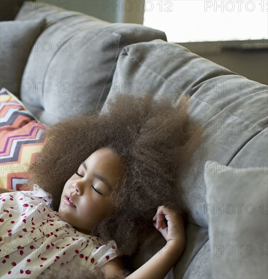 Mixed race girl sleeping on sofa