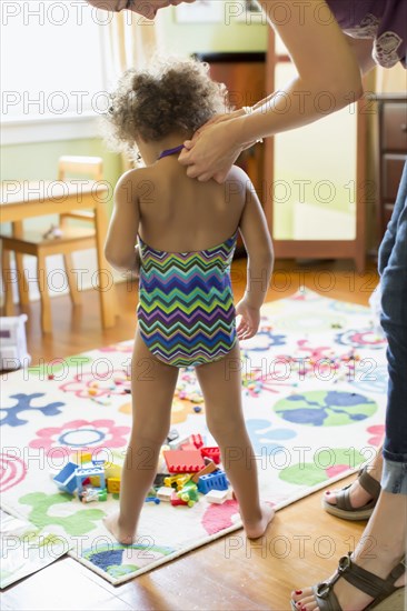 Mother putting bathing suit on daughter