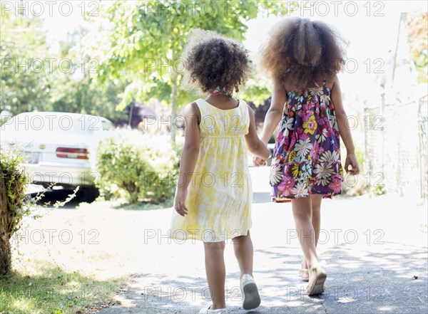 Mixed race sisters holding hands