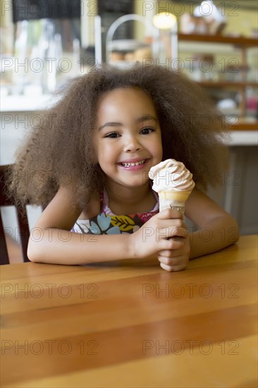 Mixed race girl eating ice cream cone