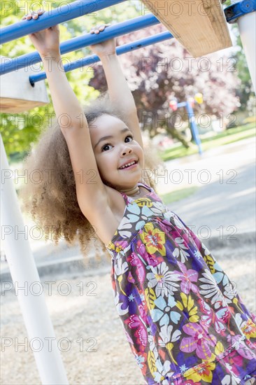 Mixed race girl hanging from bar