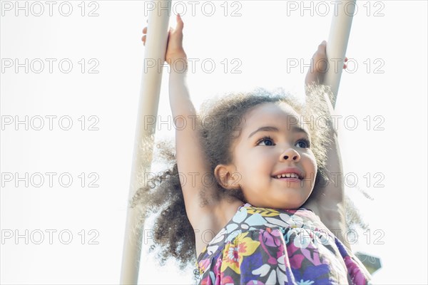 Mixed race girl hanging from bar