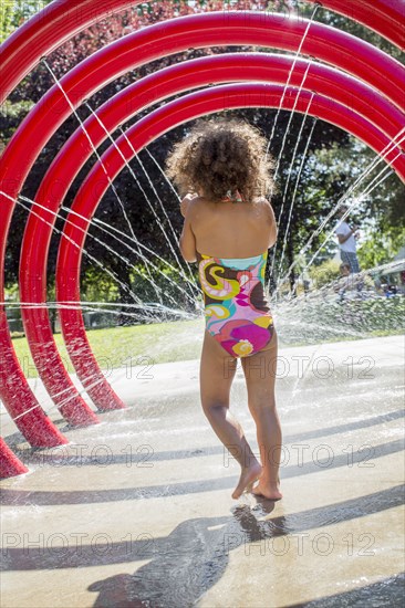 Mixed race girl playing in fountain