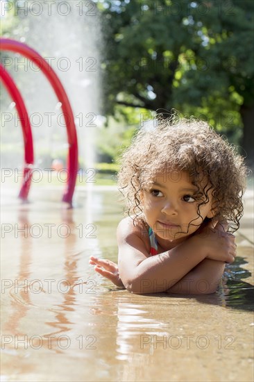 Mixed race girl playing in fountain