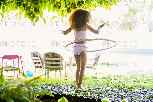 Mixed race girl twirling plastic hoop
