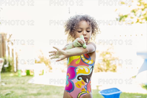 Mixed race girl putting chalk on her arm