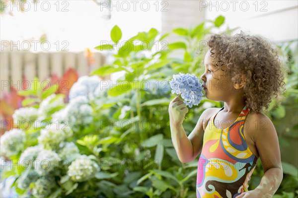 Mixed race girl smelling flower