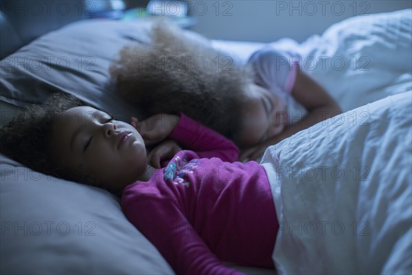 Mixed race girls sleeping in bed