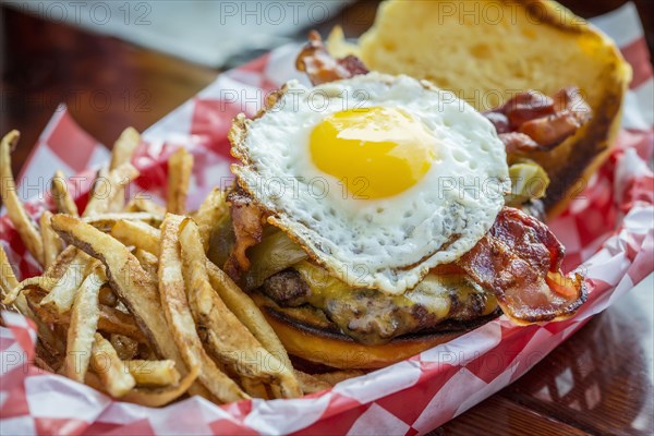 Basket of french fries with cheeseburger and egg