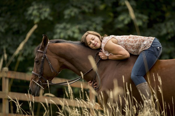 Caucasian woman laying on horse in pen