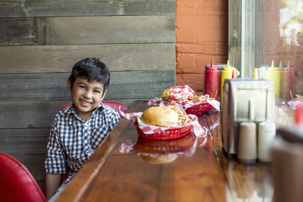 Mixed race boy having burgers in restaurant