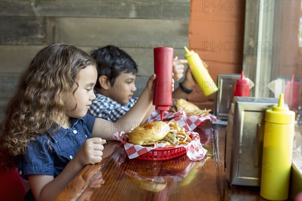 Mixed race children having burgers in restaurant