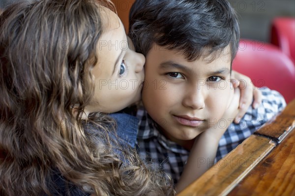 Mixed race girl kissing frowning boy