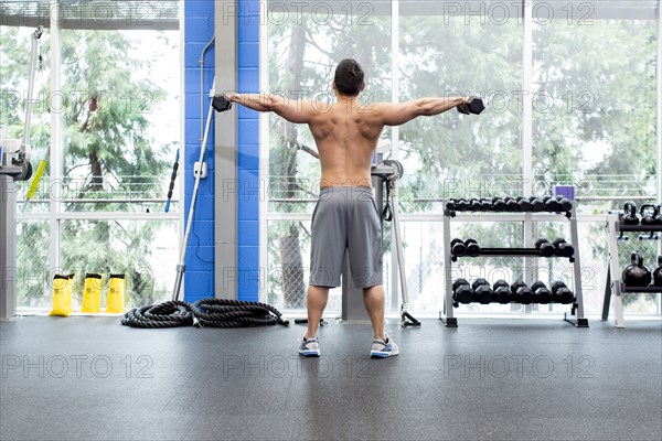 Pacific Islander man lifting weights in gym