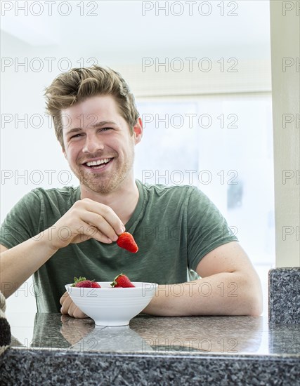 Man eating strawberries in kitchen