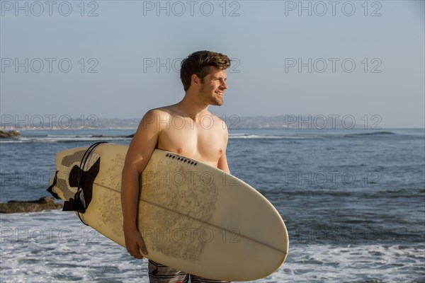 Man carrying surfboard on beach