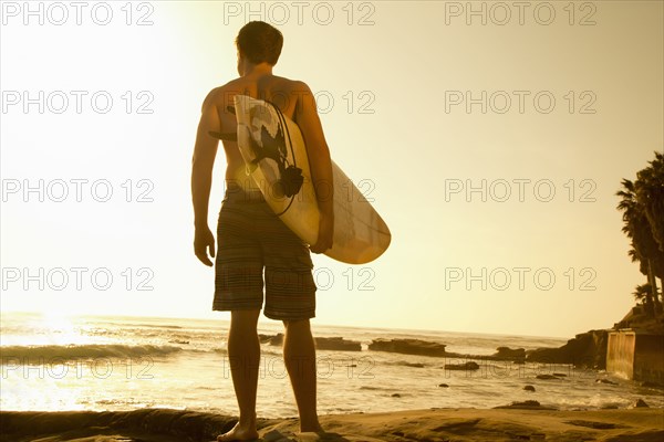 Man carrying surfboard on beach