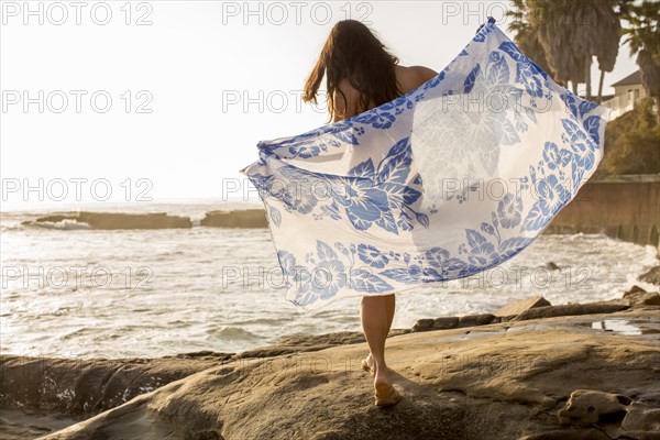 Japanese woman holding sarong on beach