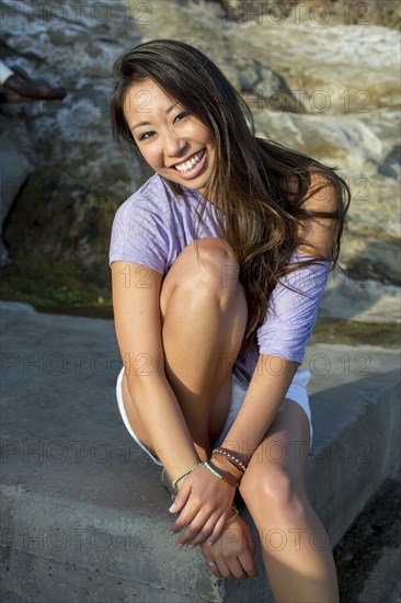 Mixed race woman smiling on rock