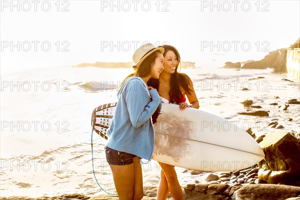 Women carrying surfboard on beach