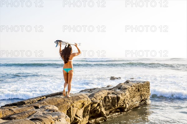 Japanese woman carrying surfboard on beach