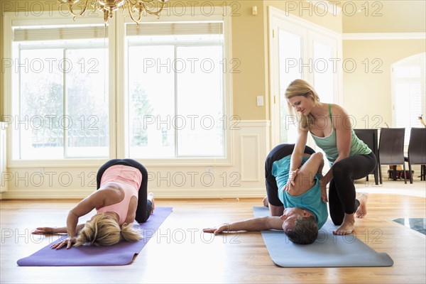 Caucasian couple working with yoga instructor in home