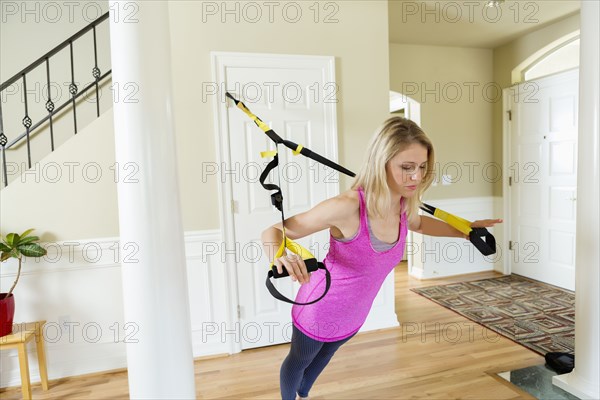 Caucasian woman using resistance band equipment in home