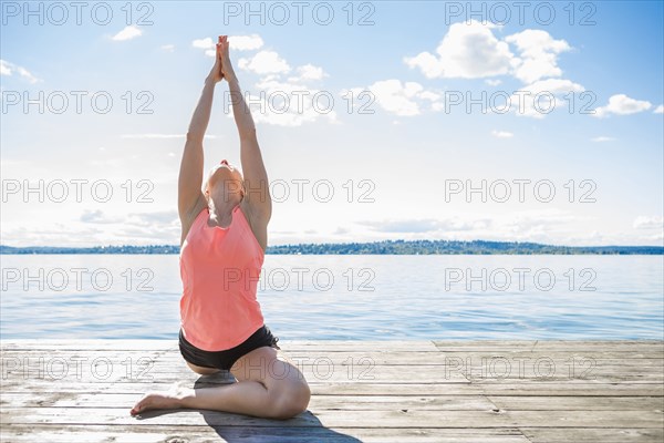 Caucasian woman practicing yoga on wooden dock