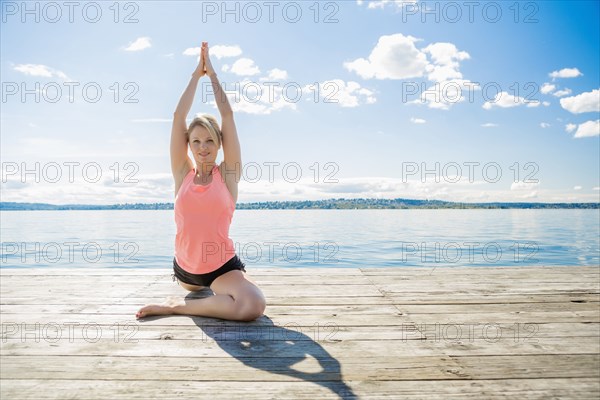 Caucasian woman practicing yoga on wooden dock