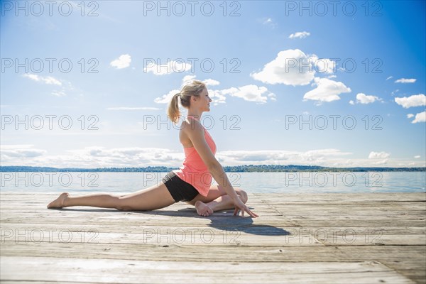 Caucasian woman practicing yoga on wooden dock