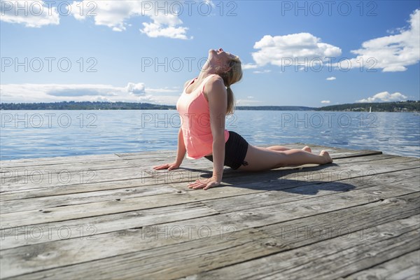 Caucasian woman practicing yoga on wooden dock